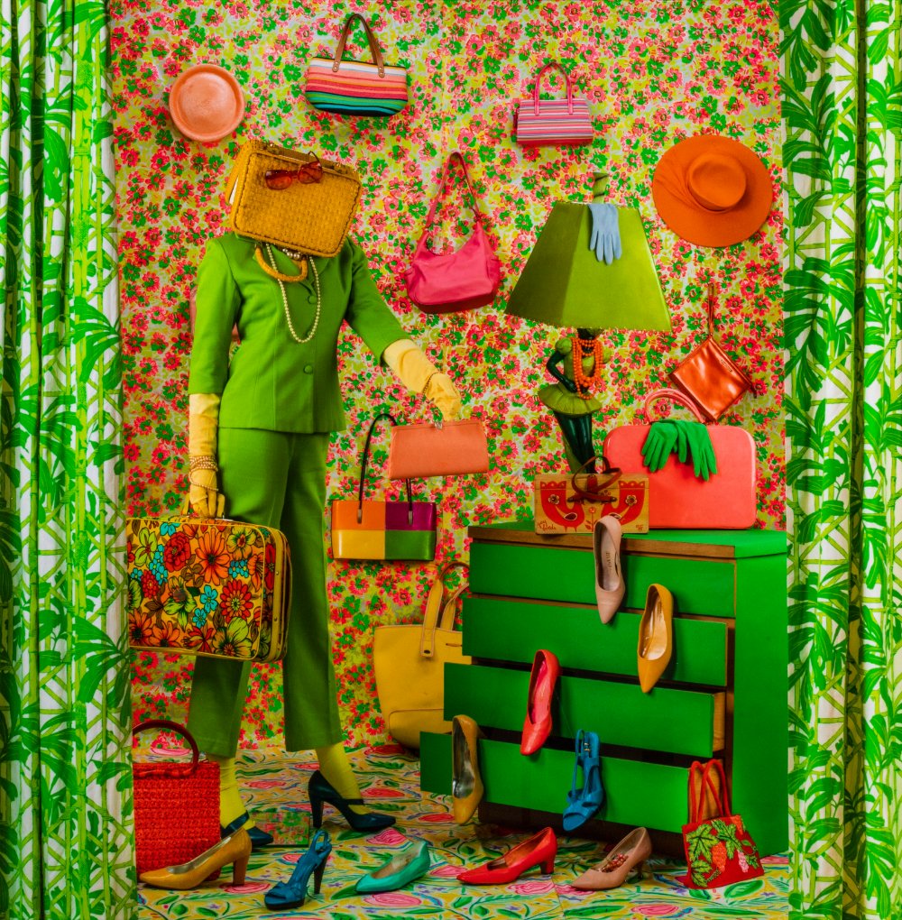 Highly patterned image of a standing figure with a purse over their head. They are holding several bags, and are surrounded by shoes. There are hats and bags on the wall behind them. A green dresser to the left had high heels coming out of the drawers.