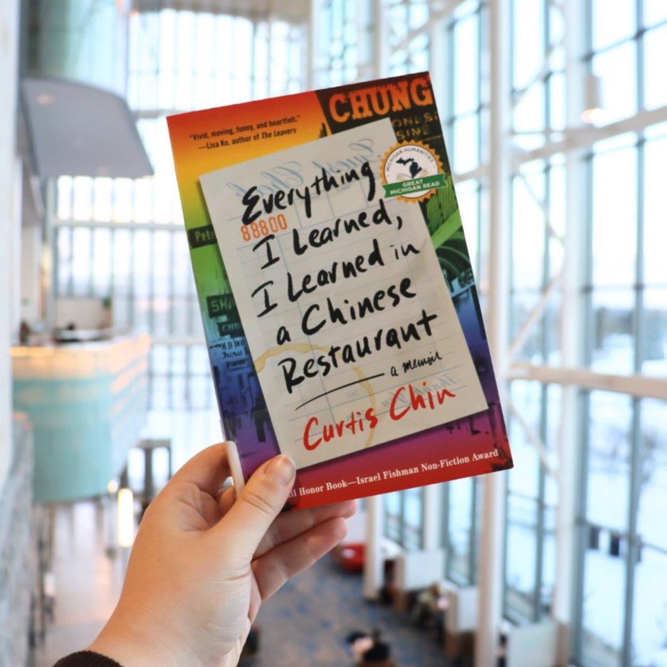 hand holding up a copy of the book, Everything I Learned, I Learned in a Chinese Restaurant by Curtis Chin.