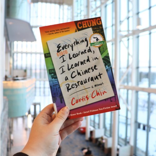 hand holding up a copy of the book, Everything I Learned, I Learned in a Chinese Restaurant by Curtis Chin.
