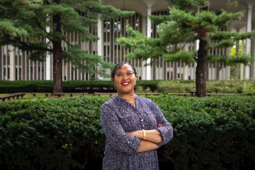 Dr. Janell Hobson- woman standing in front of greenery, arms crossed, looking at the camera
