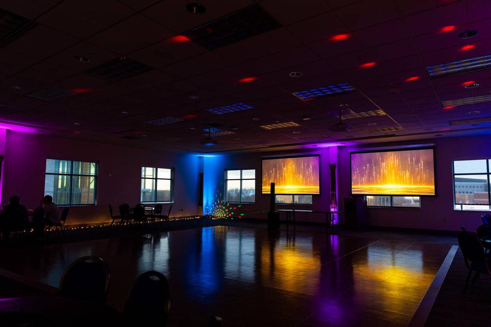 The dark dance floor with moody hot pink, blue, and golden lighting