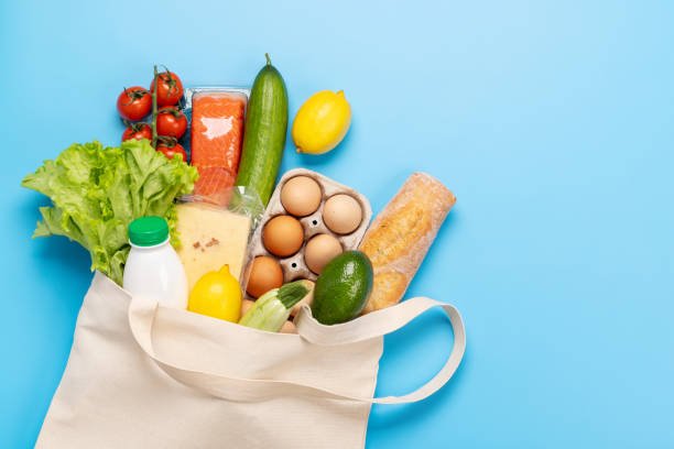 A bag of groceries featuring eggs, vegetables, and bread