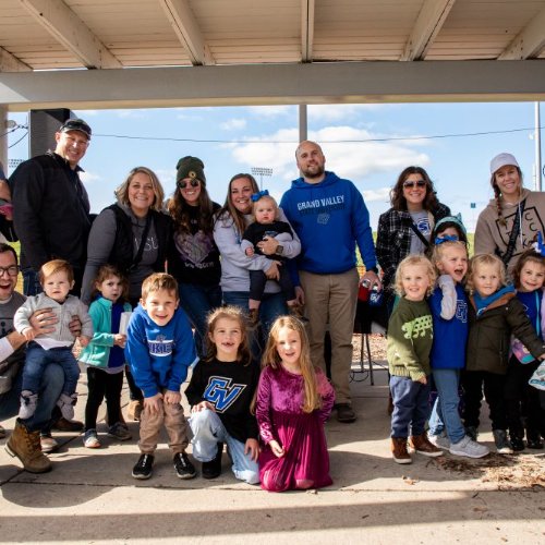 A group of family, friends and kids smile for a photo during Homecoming 2023