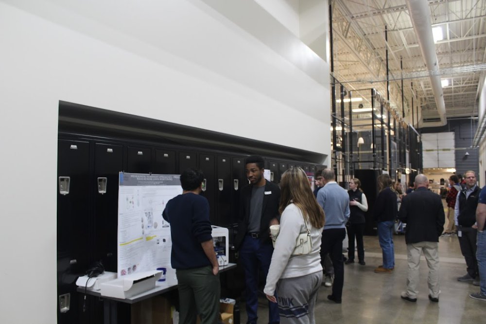 Engineering student presents project to two community members.