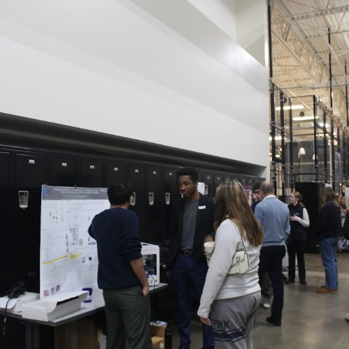 Engineering student presents project to two community members.