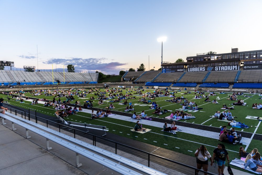 students sitting on the football field on blankets