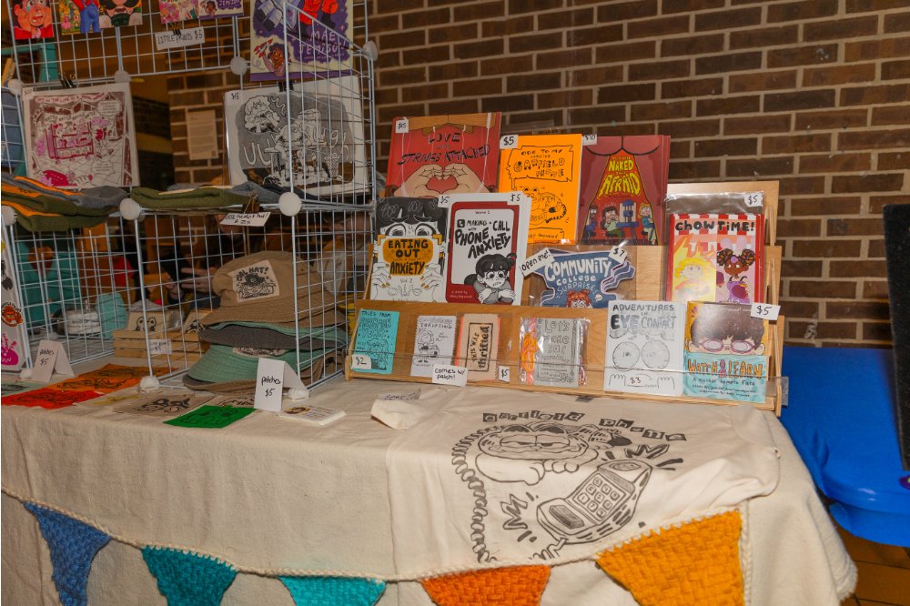 Table filled with handmade hats, prints, and other art pieces
