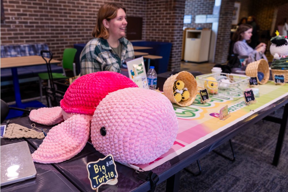 student sitting at table with crotchet animals