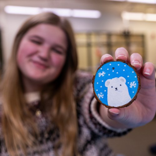 female student holding up painted ornament