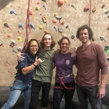 A group of people standing in front of a rock wall