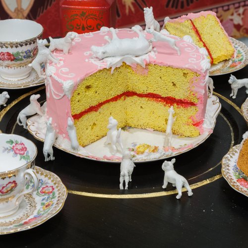 a pink cake with white toys animals around it