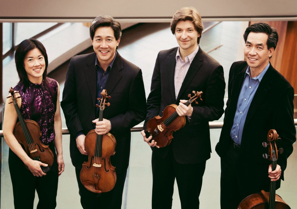 four musicians stand holding stringed instruments