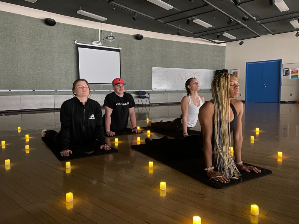 Students in upward dog on yoga mats with candle light votives.