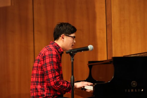 Student Daniel Belkius playing the piano and singing in French.