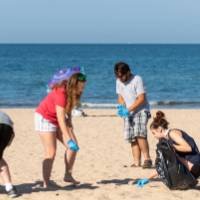 Students picking up trash on the beach.