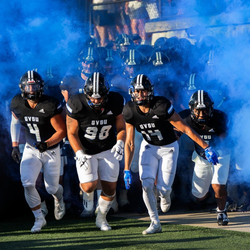 GVSU Football players run onto the field in front of blue smoke