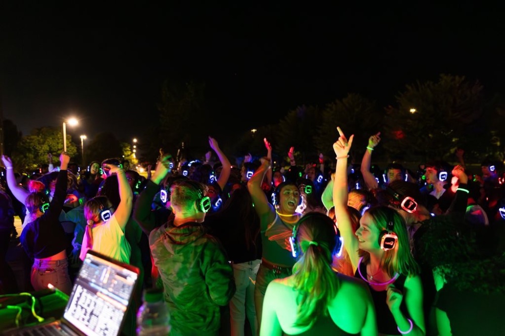 a group of students with headphones on jumping up and down