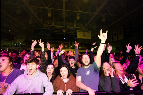 students at concert with hands in the air