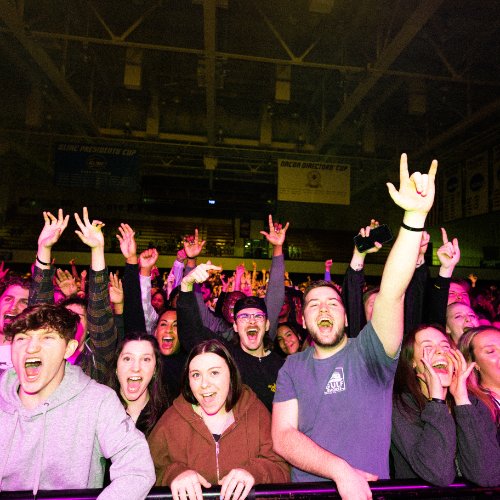students at concert with hands in the air