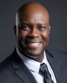 african american male in dark suit, white shirt and dark tie smiling