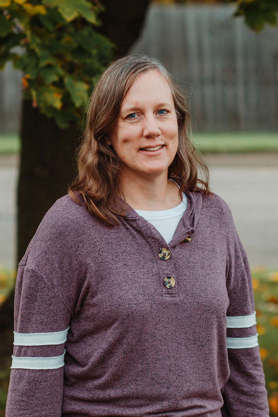 Bev Harkema stands outside in front of a tree