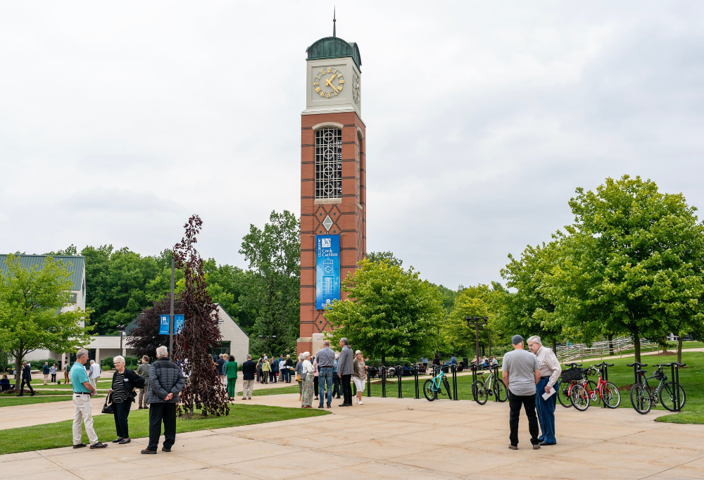 people milling around the base of the Cook Carillon Tower, in center of photo on sidewalks of GVSU's Allendale Campus