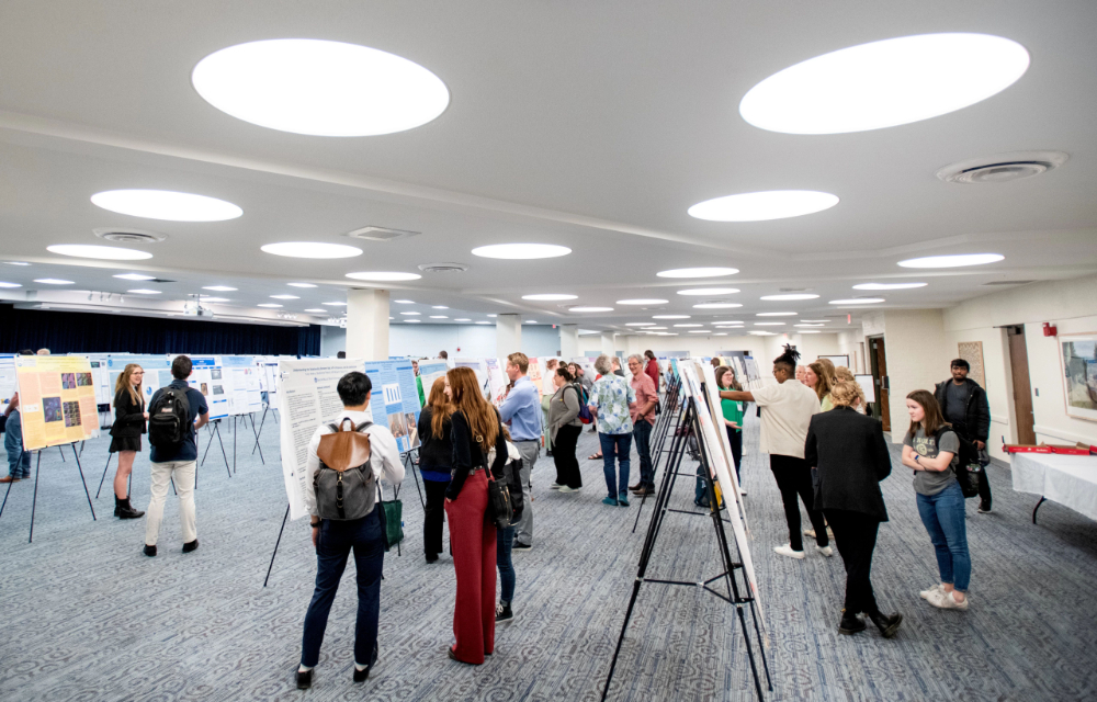 room of posters on easels and people looking at posters and chatting