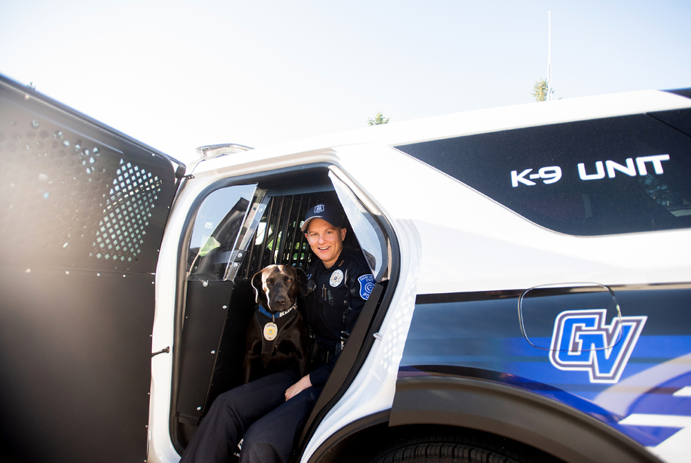 police officer and K-9 dog sitting in a new police SUV cruiser with K-9 Unit and GV as decals in back rear panel