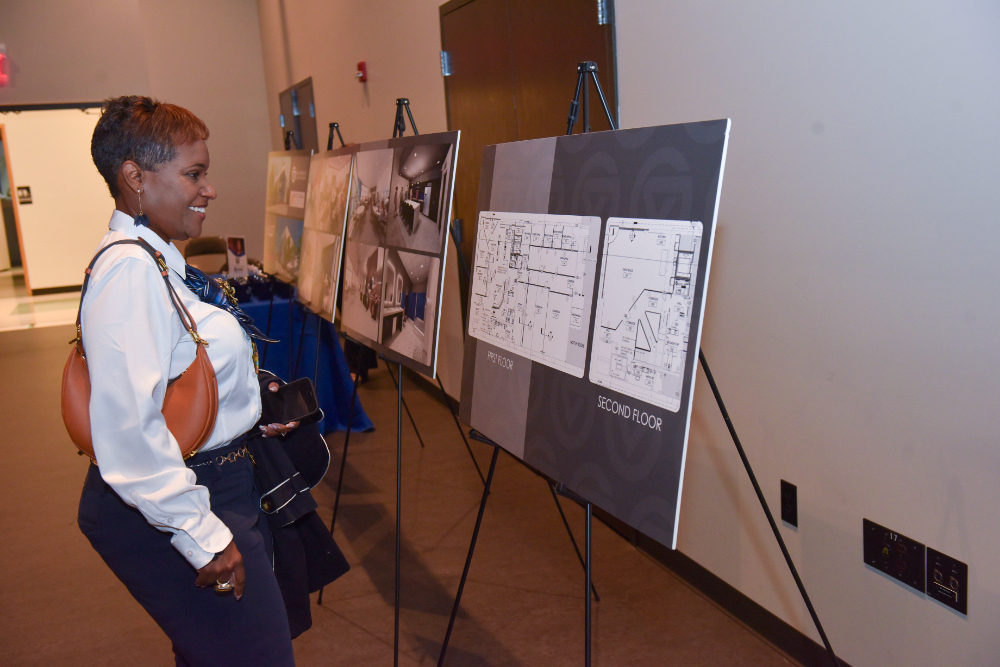 woman stands to look at poster boards of renderings for the new Battle Creek Innovation Hub
