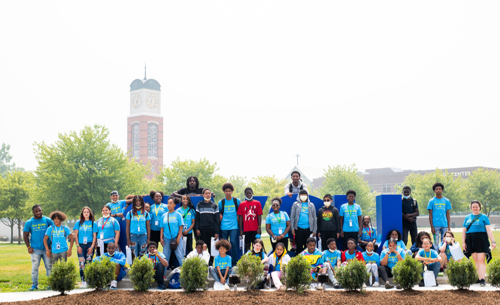 group of middle school students in front of the Laker Letters, carillon tower in the background