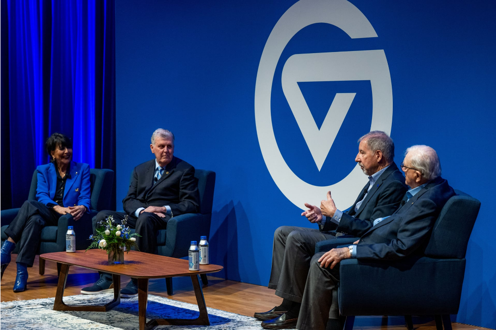 Seated on stage at the DeVos Center are from left, President Mantella, Thomas Haas, Mark Murray and Don Lubbers. They are in front of a GV backdrop