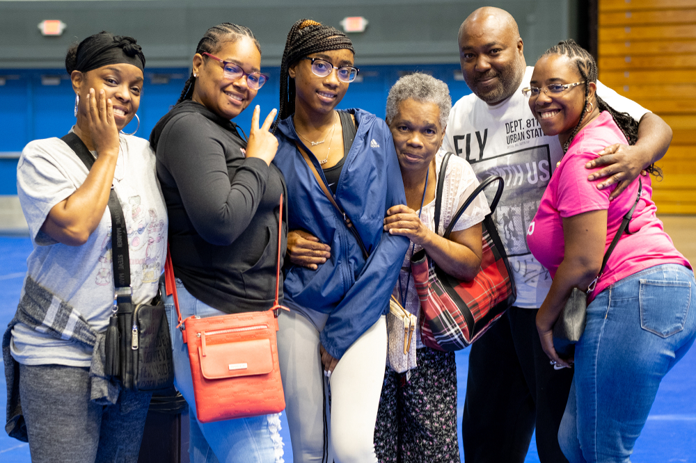 six people posing in a line inside the Fieldhouse