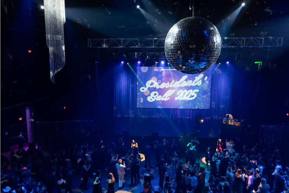 dancers on the floor, a large disco ball hung from the ceiling and Presidents' Ball 2025 on the projection screen