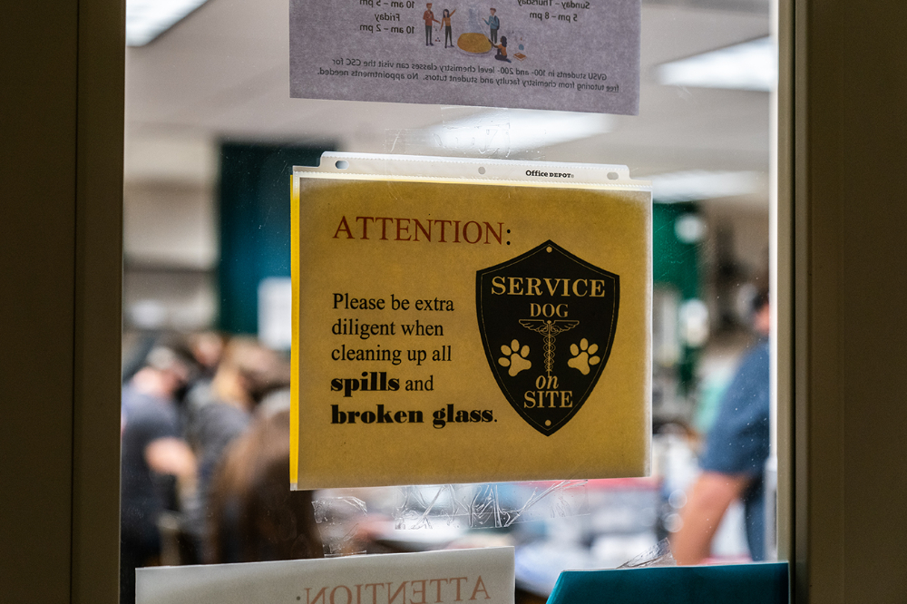 sign on the door warns of a service dog and to clean up broken glass