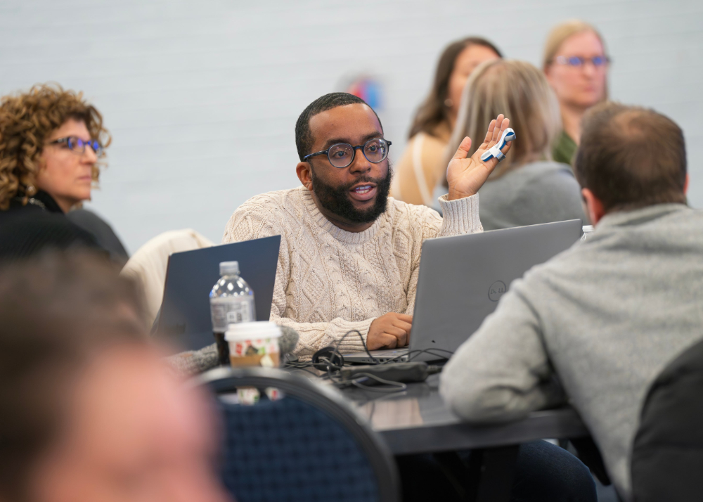 people seated at round tables with laptops open