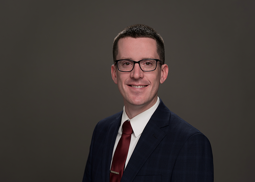 Jason Cronkrite seated in blue suit