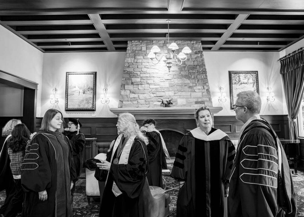 black and white photo of four people in academic regalia