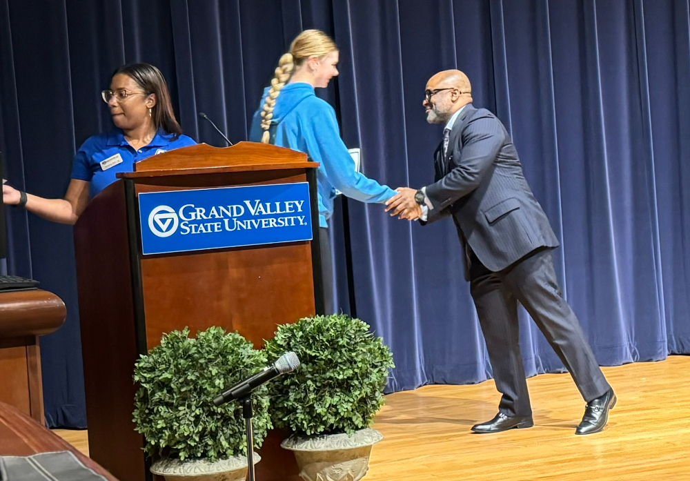 VP Truss shakes the hand of a high school student as she accepts a certificate; person behind podium hands certificate to next person in line
