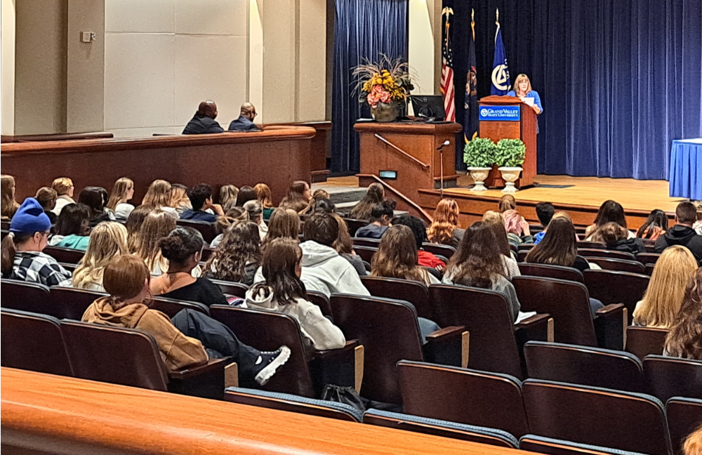 Amy Schelling speaks in Loosemore Auditorium, people seated in audience in rows