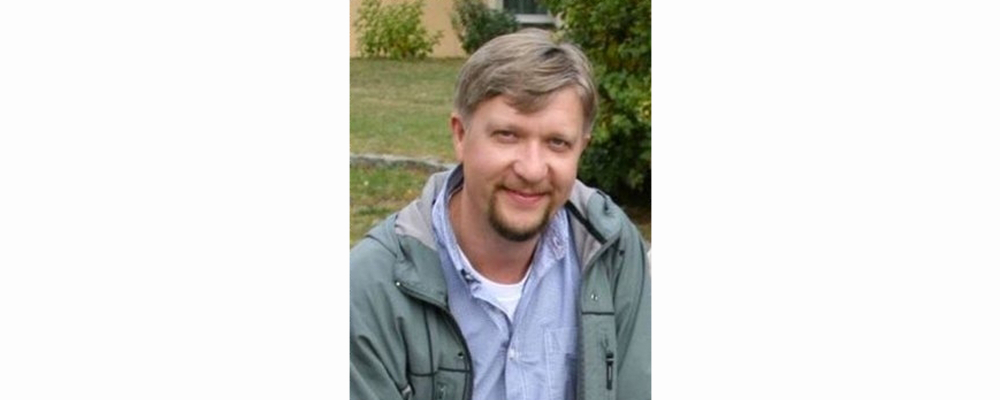 photo of Alex Nikitin, seated outside in a jacket