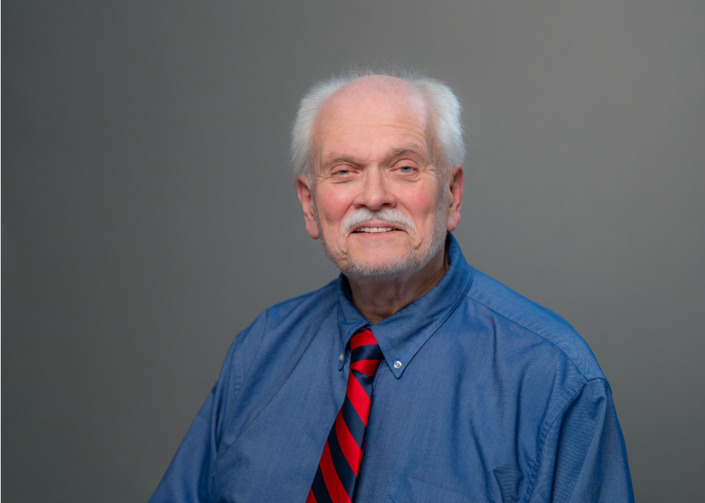 Alex Nesterenko portrait, wearing a blue shirt with blue and red striped tie