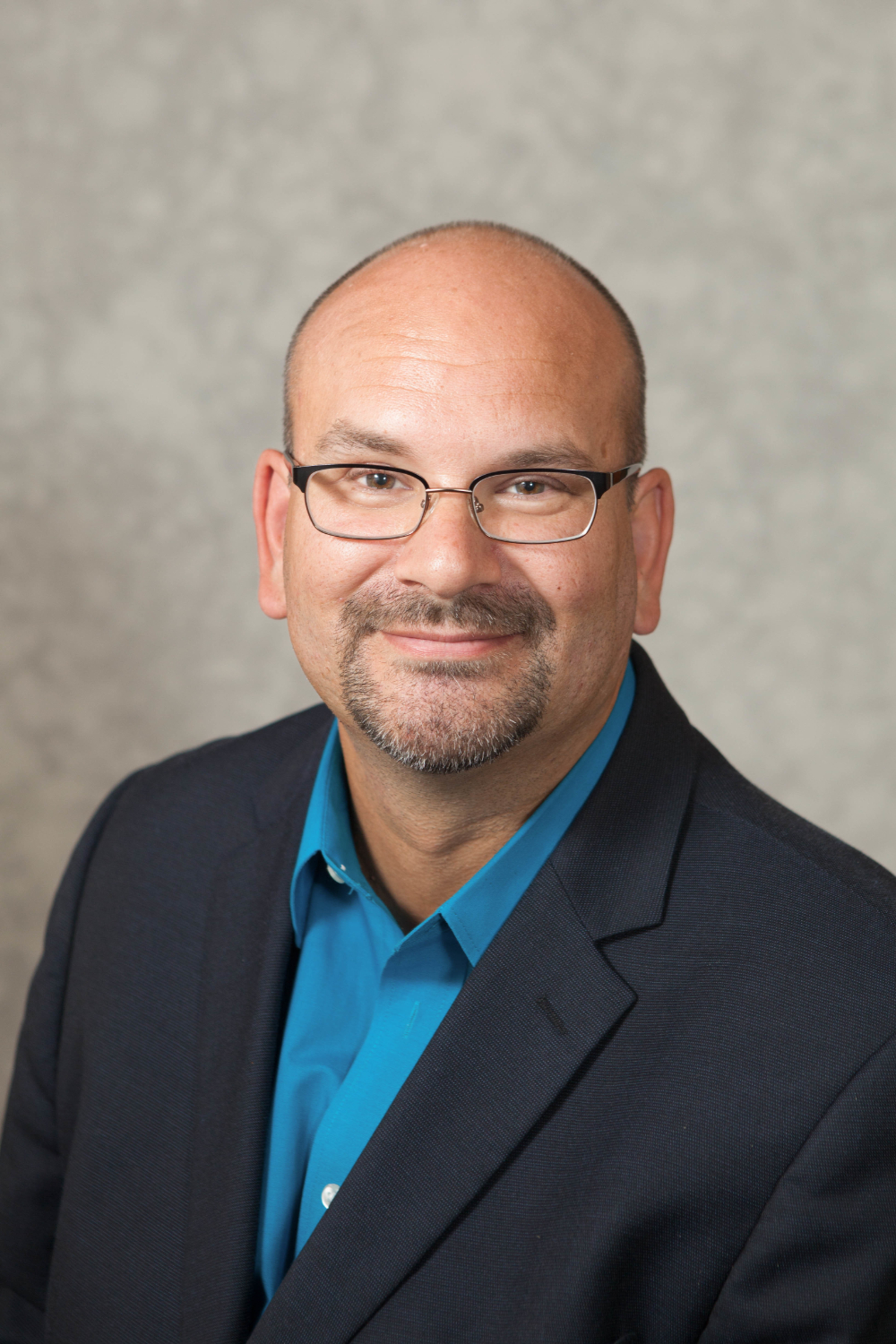 Kevin Strychar in a dark jacket and blue shirt, wearing glasses