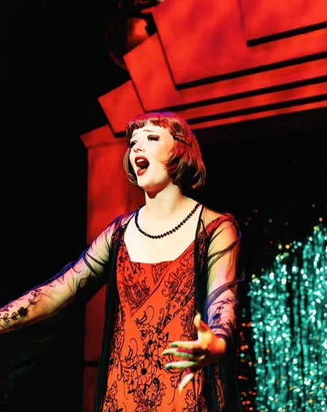 Lindsey Normington in dress on stage singing