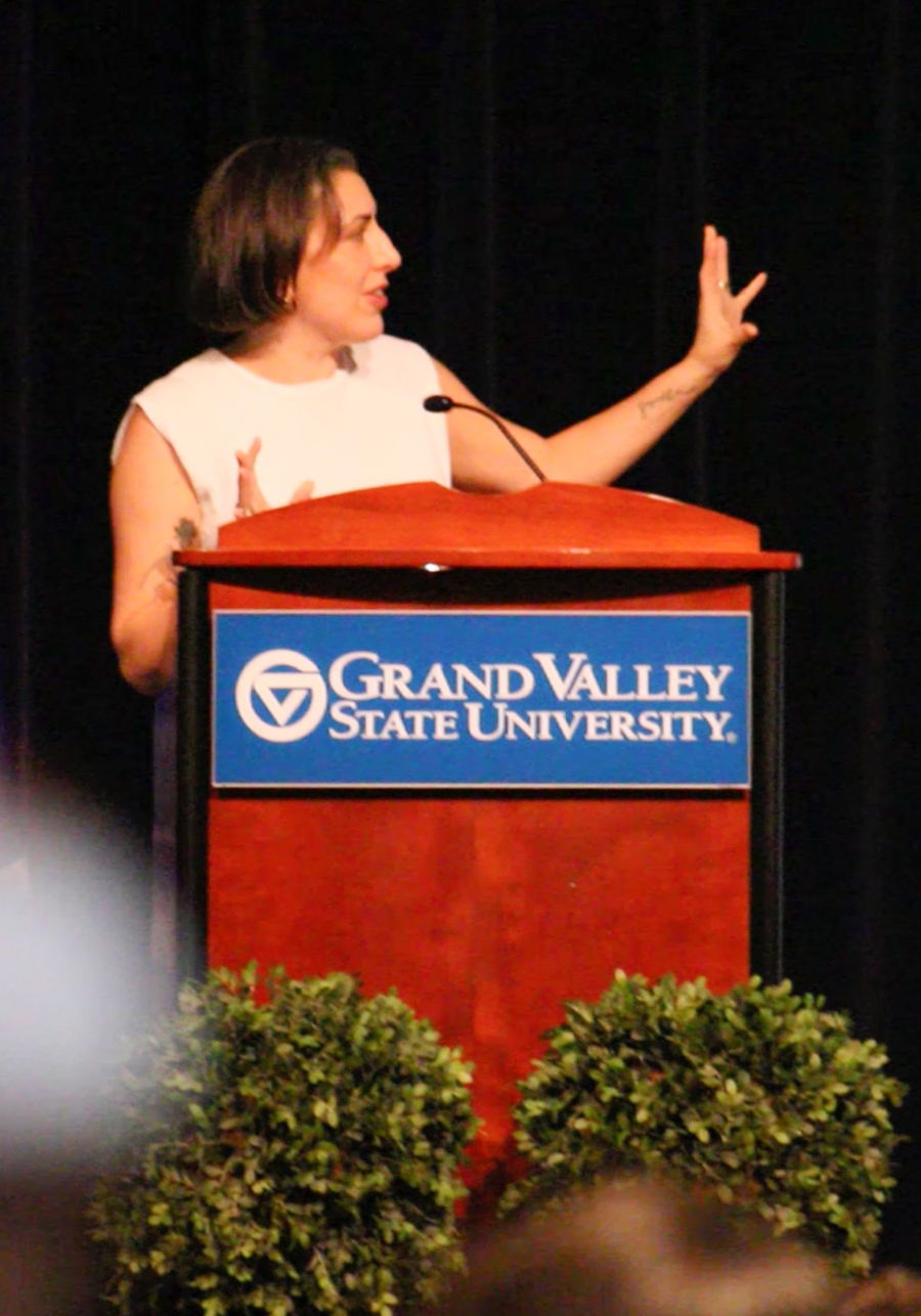 Jessica Valenti behind podium with arm raised looking at center stage