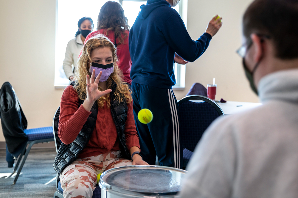students seated in chairs toss a tennis ball back and forth