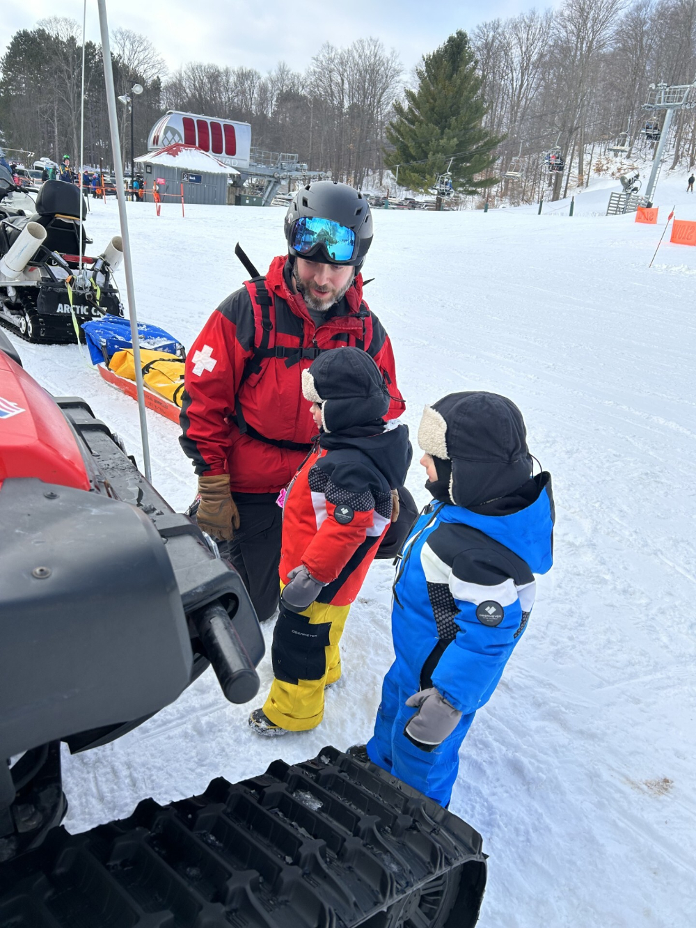 A man and two young boys, all in ski clothes, prepare to board a ski lift.