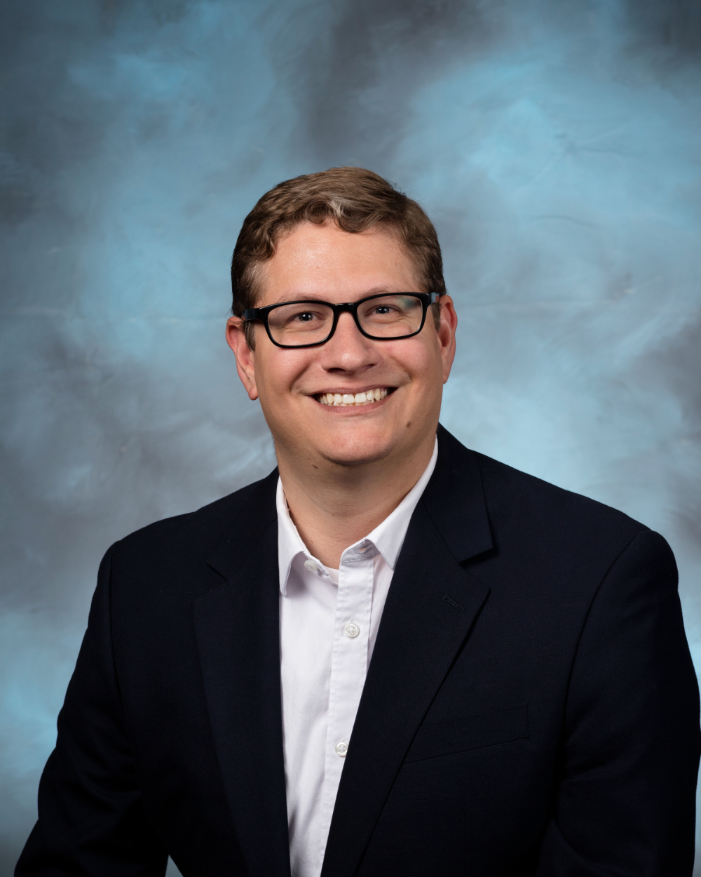 Alex Plotkowski in dark suit jacket and white shirt