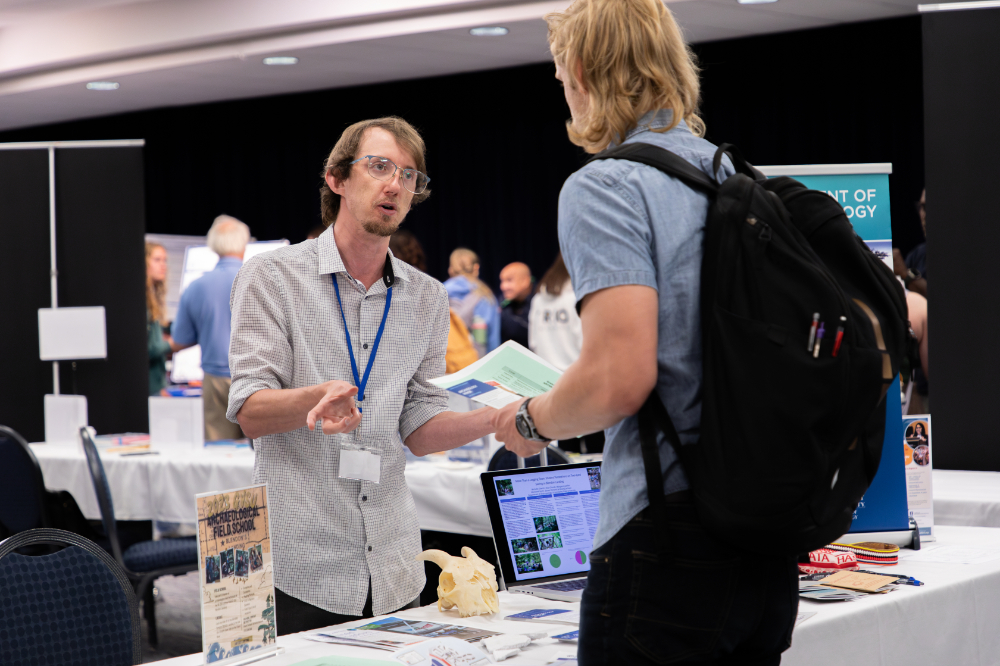 two people talk across a table at the undergraduate research fair