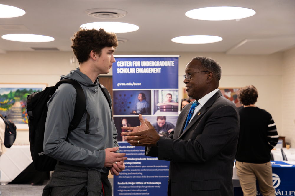 two people standing to talk in the background is the Center for Undergraduate Scholar Engagement vertical banner