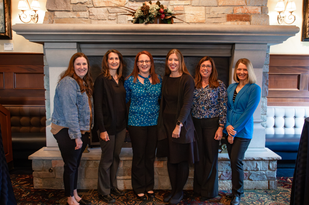 six people standing in front of a fireplace